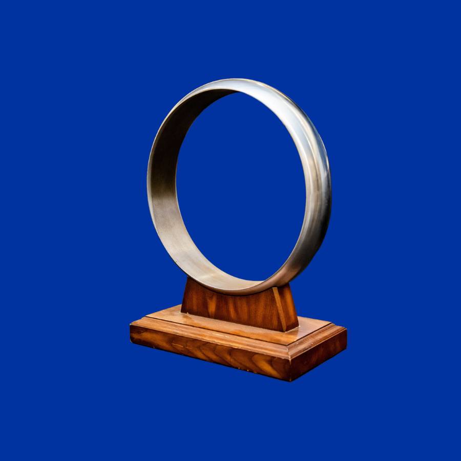 Ceremony ring. A large metal ring on a wooden base in front of a blue background